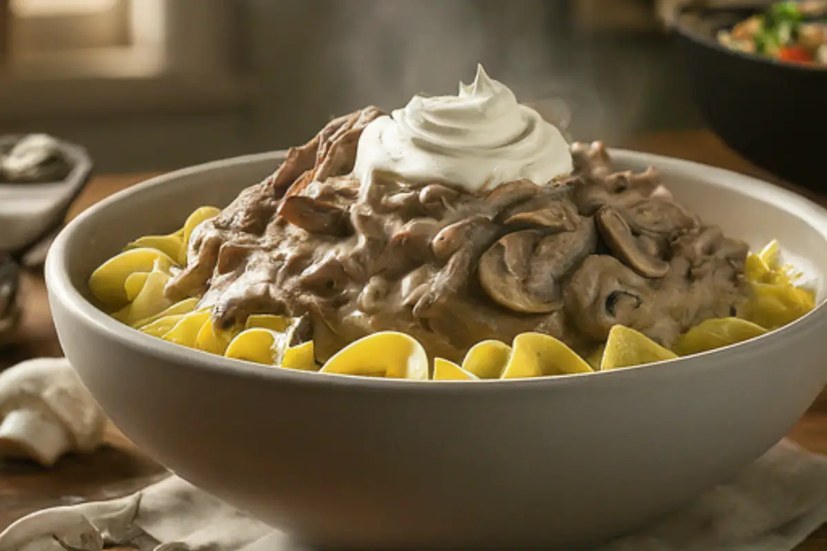 A steaming bowl of creamy stroganoff with tender shredded chuck roast, mushrooms, onions, and a dollop of sour cream.